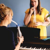 Gesangslehrerin und Schülerin arbeiten am Klavier mit LAX VOX® an der Gesangsstimme